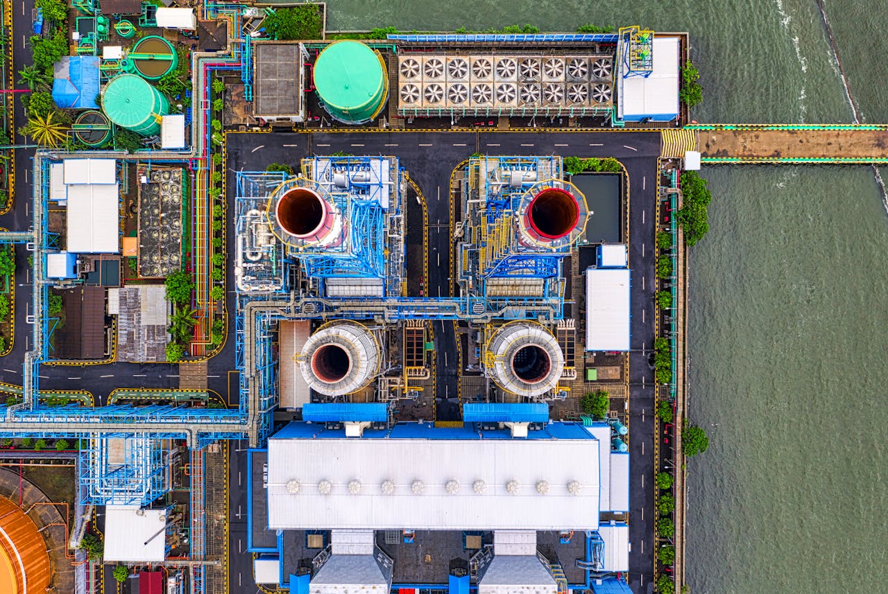 Aerial view of an industrial plant in Jakarta by the waterfront. Features colorful structures and piping.